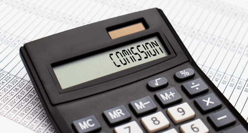 Close-up of a calculator showing ‘Commission’ on screen over financial data sheets, symbolising revenue, planning, and financial management.