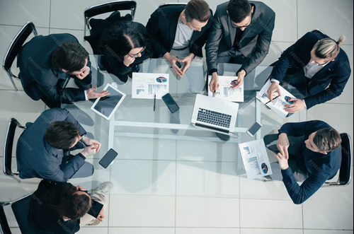 Overhead view of professionals collaborating in a meeting with laptops and reports, representing teamwork, strategy, and business growth.